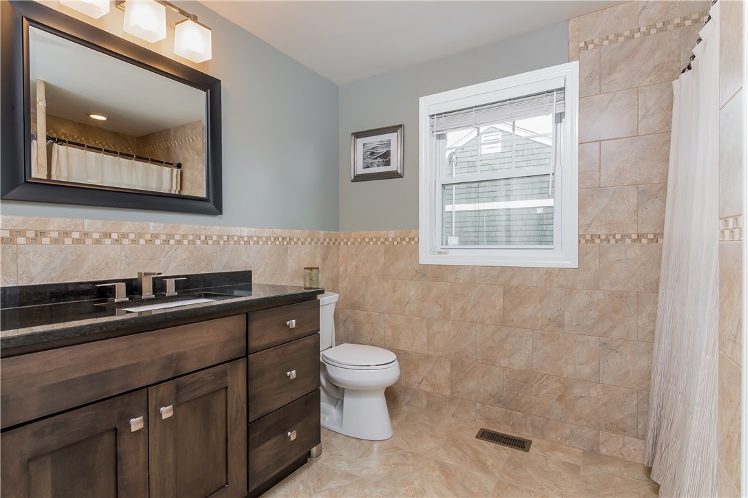 13 Nautilus Road Narragansett, RI 02882 - Photo 14 of 40 First floor bathroom with custom vanity, tiled flooring and walls, laundry area, and an over-sized walk-in shower!