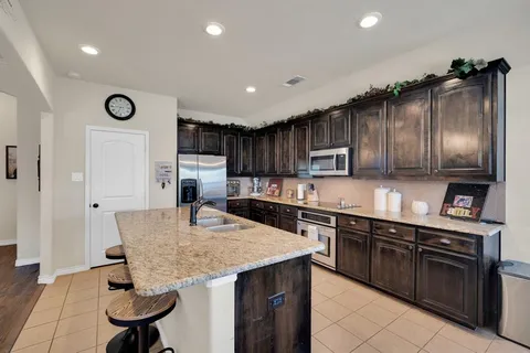 a kitchen with stainless steel appliances granite countertop a sink refrigerator and cabinets