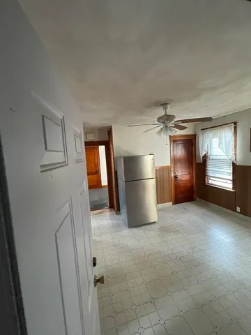 a view of an empty room and a kitchen