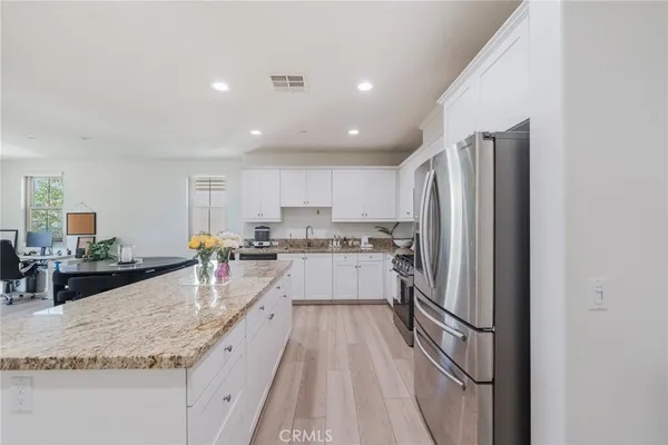 a large kitchen with kitchen island a large counter top appliances and cabinets