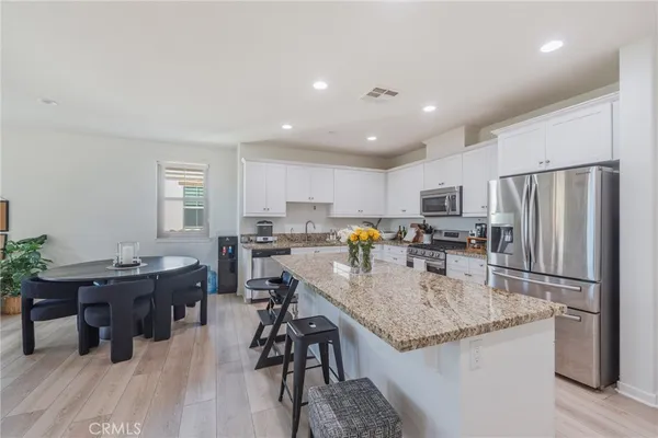 a kitchen with stainless steel appliances granite countertop table chairs refrigerator and microwave