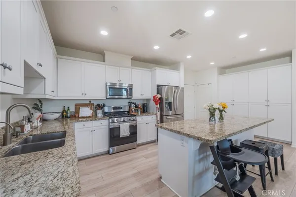 a kitchen with granite countertop a sink white cabinets and stainless steel appliances