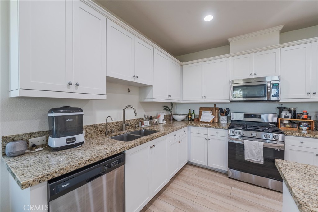 409 Mallorca Lane Brea, CA 92823 - Photo 9 of 40 a kitchen with granite countertop a sink white cabinets and stainless steel appliances