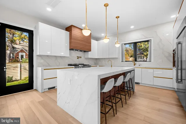 a kitchen with stainless steel appliances granite countertop a stove a sink a oven a dining table and chairs with wooden floor