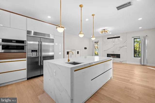 a kitchen with stainless steel appliances kitchen island granite countertop a refrigerator a sink dishwasher a stove and white cabinets with wooden floor