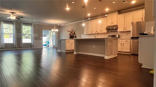 a view of kitchen with stainless steel appliances granite countertop a stove top oven a sink dishwasher a refrigerator and white cabinets with wooden floor