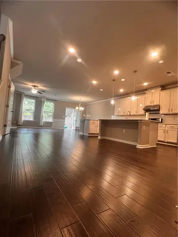 a view of a big room with wooden floor and a kitchen