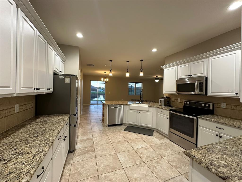 3008 Boat Lift Road Kissimmee, FL 34746 - Photo 17 of 56 a large kitchen with stainless steel appliances kitchen island granite countertop a sink and cabinets