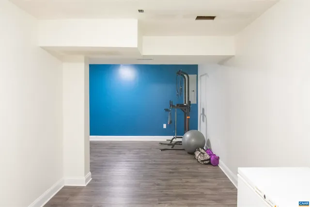 a spacious bedroom with a bed ceiling fan and a wooden floor
