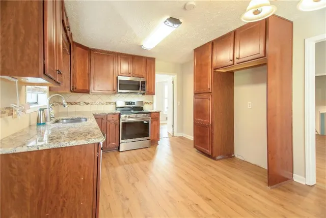 a kitchen with stainless steel appliances granite countertop a refrigerator a sink dishwasher and wooden cabinets with wooden floor