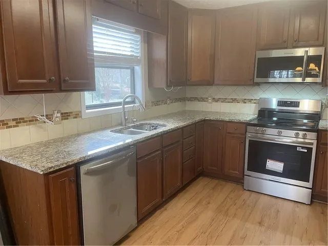 a kitchen with granite countertop a sink cabinets and stainless steel appliances