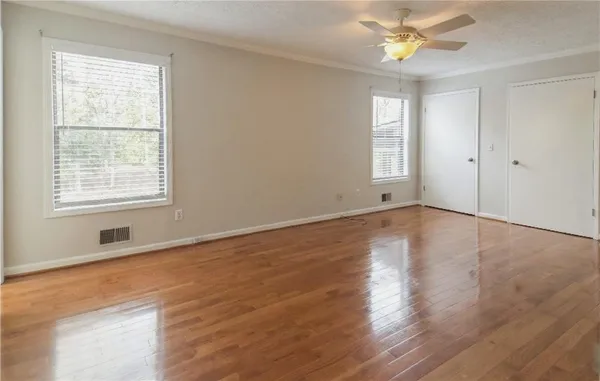 an empty room with wooden floor and windows
