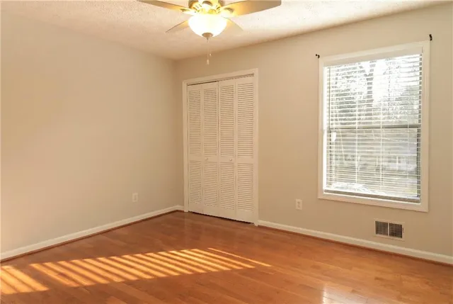 a view of an empty room with wooden floor and a window