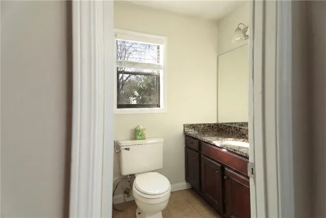 a bathroom with a granite countertop toilet and a sink