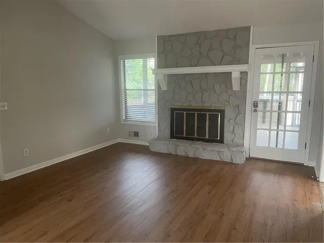 an empty room with wooden floor fireplace and windows