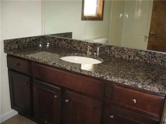 a bathroom with a granite countertop sink a mirror and vanity