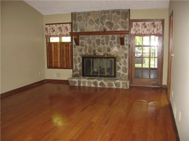 an empty room with wooden floor and fireplace