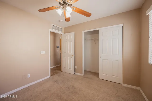 an empty room with closet and a chandelier fan