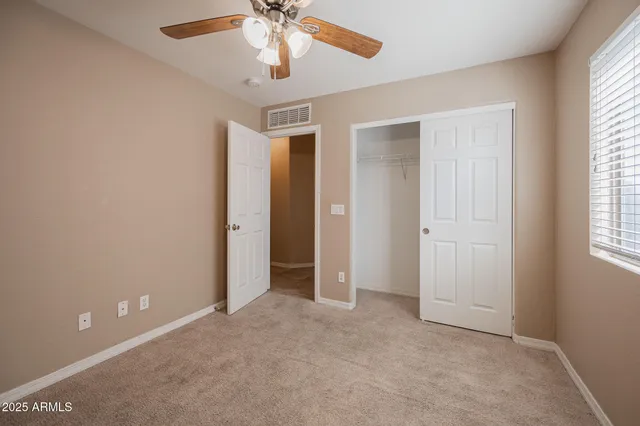 an empty room with windows and fan