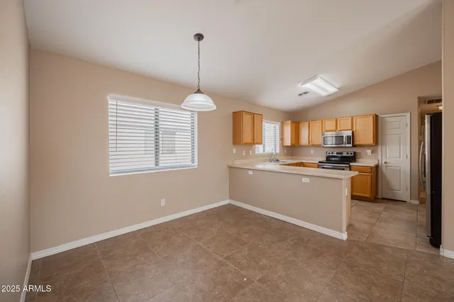 a kitchen with stainless steel appliances granite countertop a refrigerator a sink dishwasher a stove and white cabinets with wooden floor