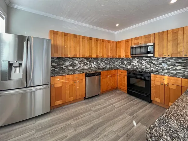a kitchen with stainless steel appliances granite countertop a refrigerator a sink and a stove
