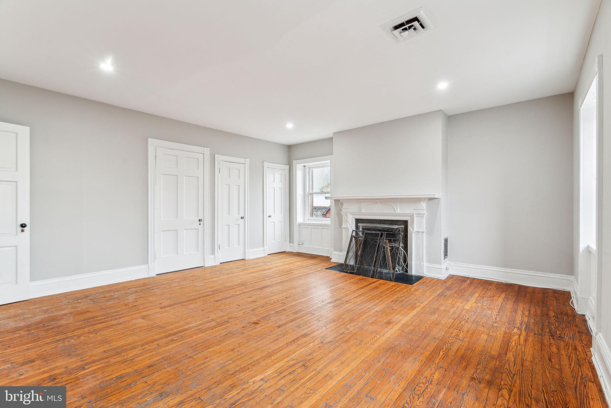 2101 Spruce Street, Unit 4F Philadelphia, PA 19103 - Photo 7 of 24 a view of an empty room with wooden floor fireplace and a window