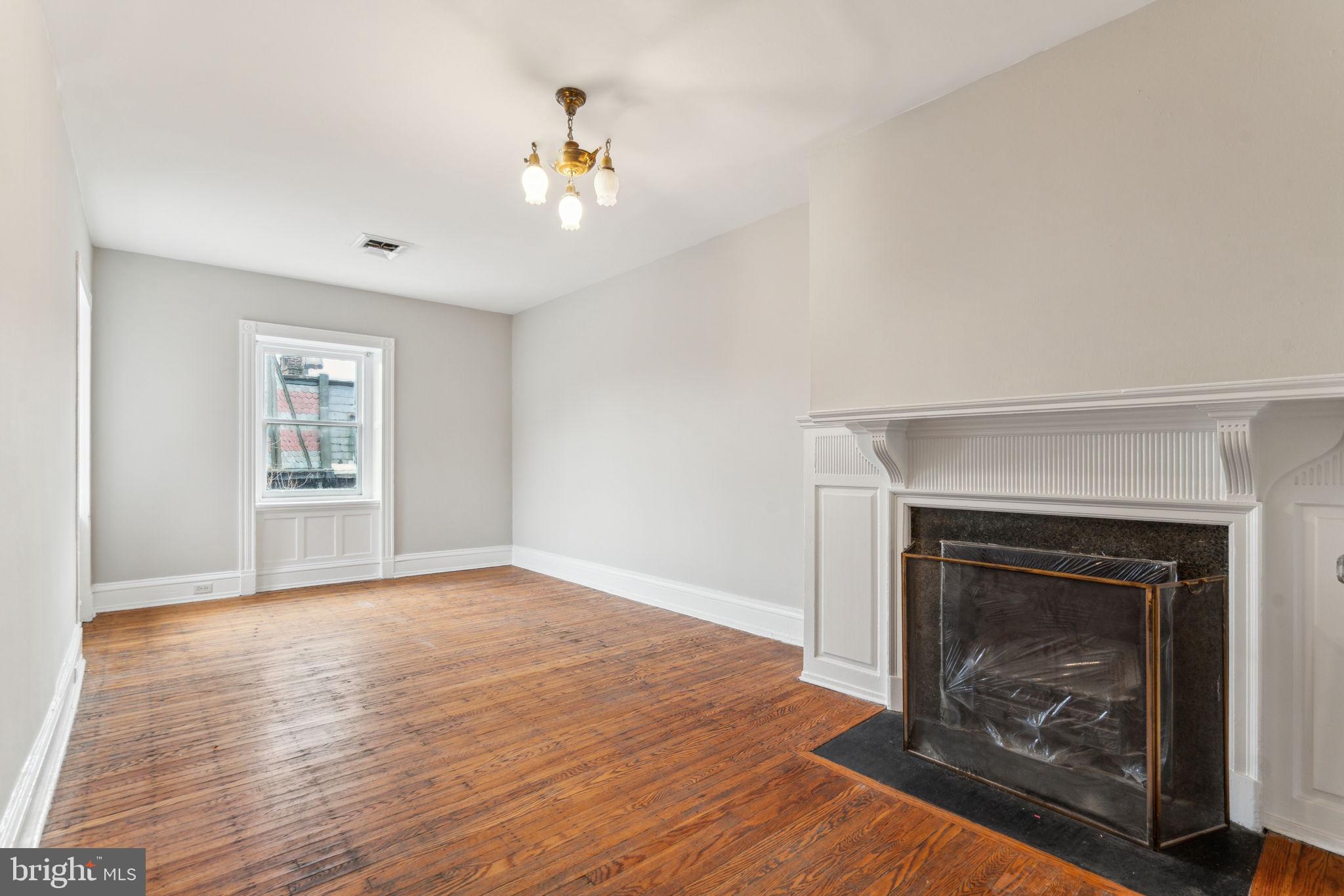 2101 Spruce Street, Unit 4F Philadelphia, PA 19103 - Photo 10 of 24 a view of an empty room with wooden floor fireplace and a window
