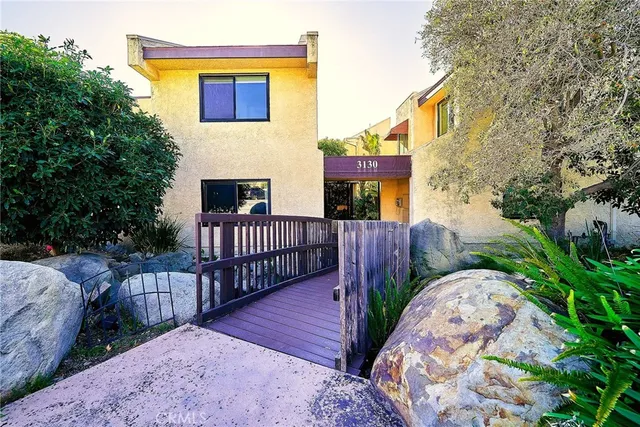 a view of a house with wooden fence and a bench in a patio