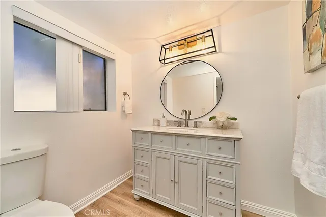 a bathroom with a toilet mirror vanity and a sink