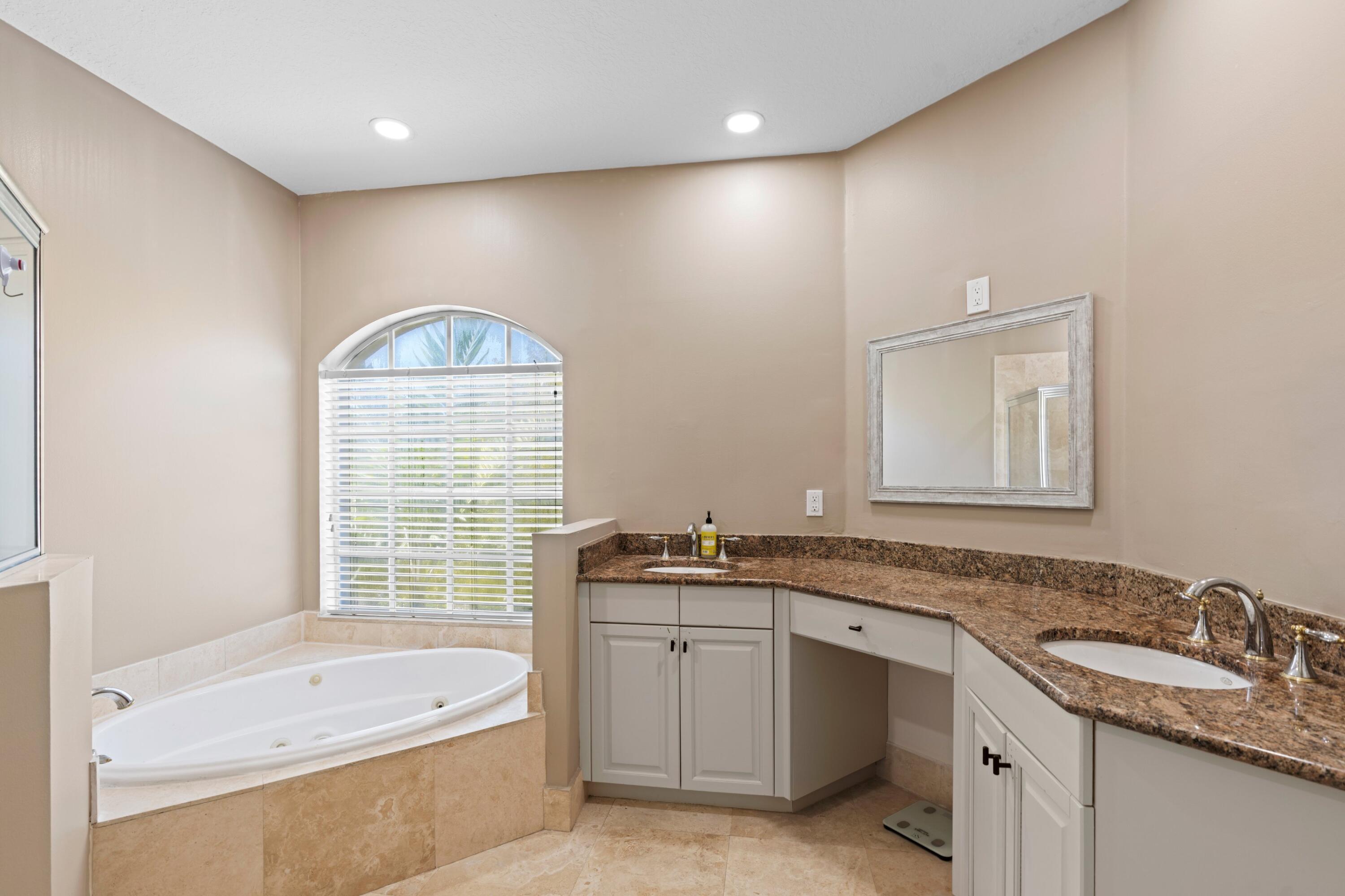 230 Northeast 69th Circle Boca Raton, FL 33487 - Photo 15 of 49 a bathroom with a granite countertop bathtub a sink and a window