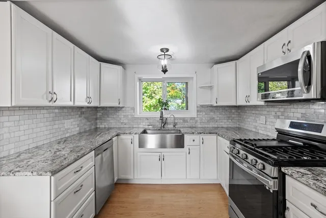 a kitchen with stainless steel appliances granite countertop white cabinets granite counter tops and a window