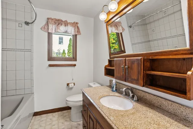 a bathroom with a granite countertop sink a toilet a mirror and shower