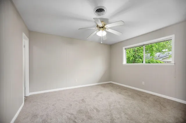 an empty room with a window and a fan