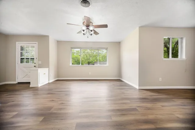 an empty room with wooden floor and windows