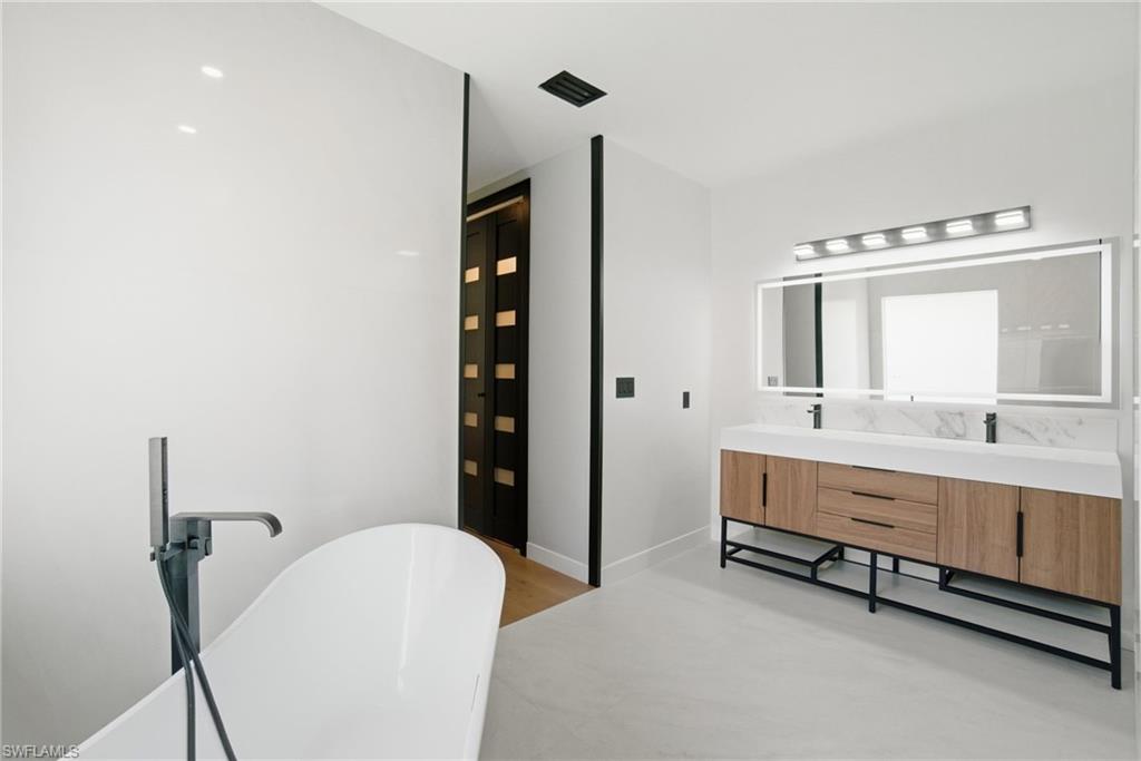 1506 Jewel Naples, FL 34102 - Photo 21 of 49 a bathroom with a double vanity sink a mirror and a bathtub