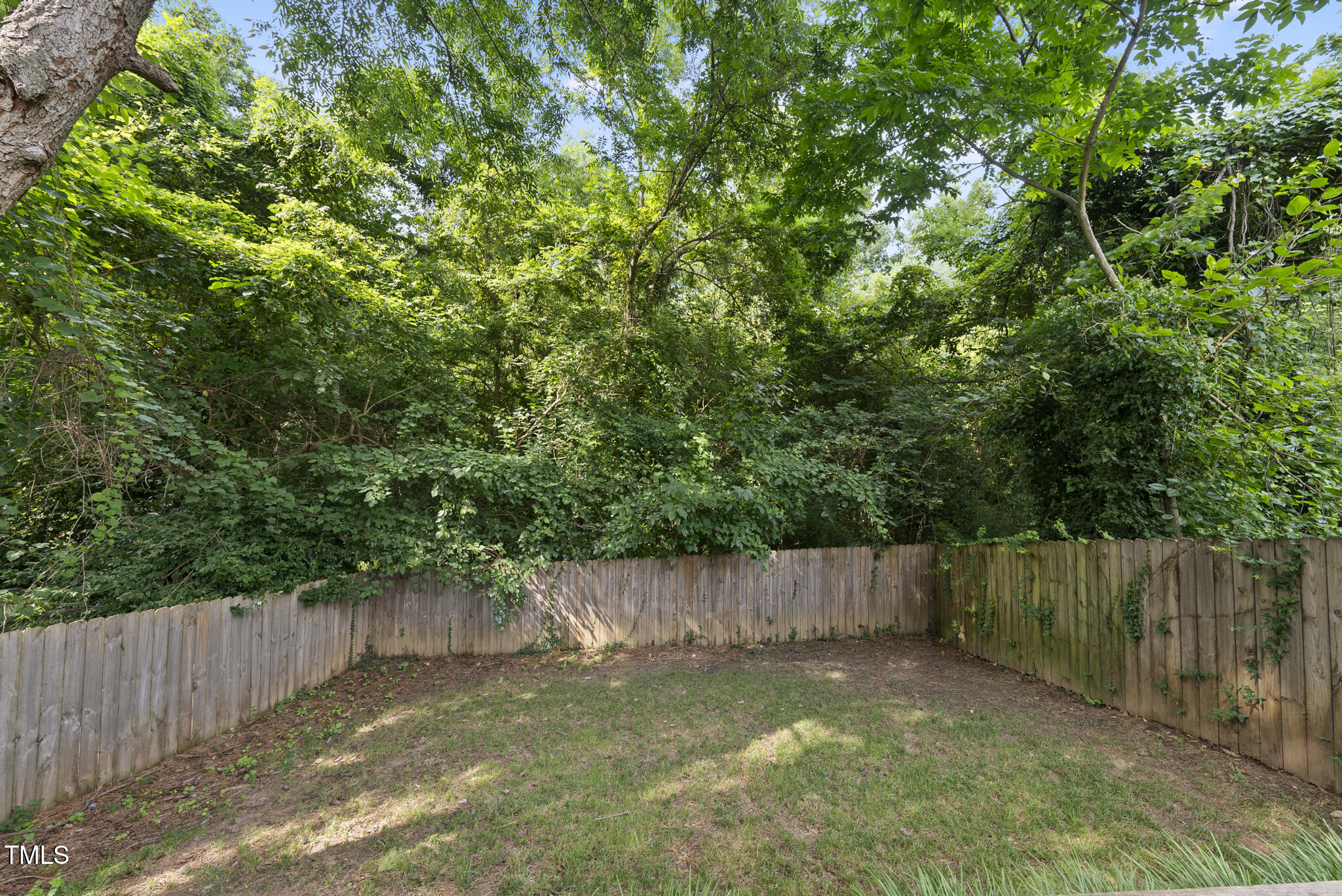 1529 Battery Drive Raleigh, NC 27610 - Photo 32 of 34 a view of a backyard with wooden fence and a large tree
