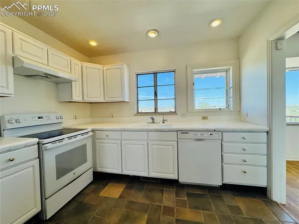 a kitchen with granite countertop white cabinets stainless steel appliances a sink and a window