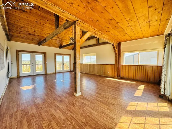 a view of empty room with wooden floor and fan