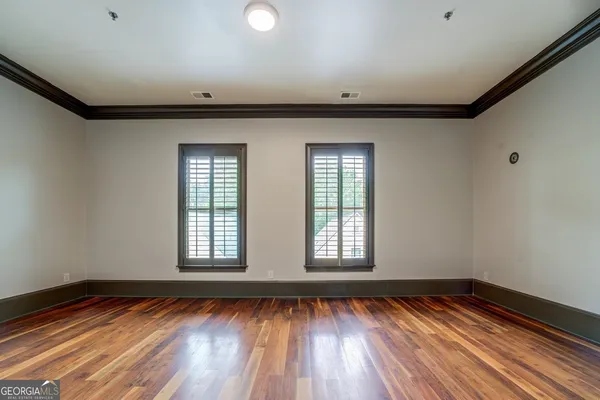 a view of an empty room with wooden floor and window