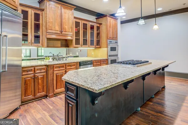 a kitchen with stainless steel appliances granite countertop a sink a stove and a wooden floors
