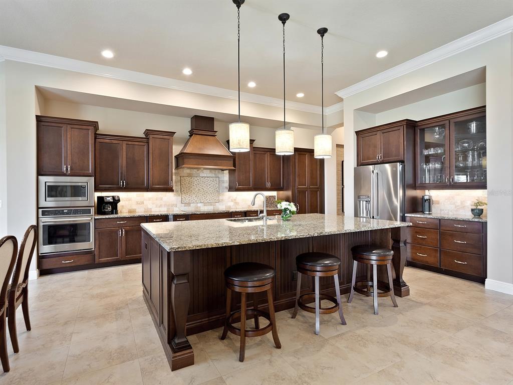 11708 Rive Isle Run Parrish, FL 34219 - Photo 12 of 65 a kitchen with kitchen island granite countertop wooden cabinets and stainless steel appliances
