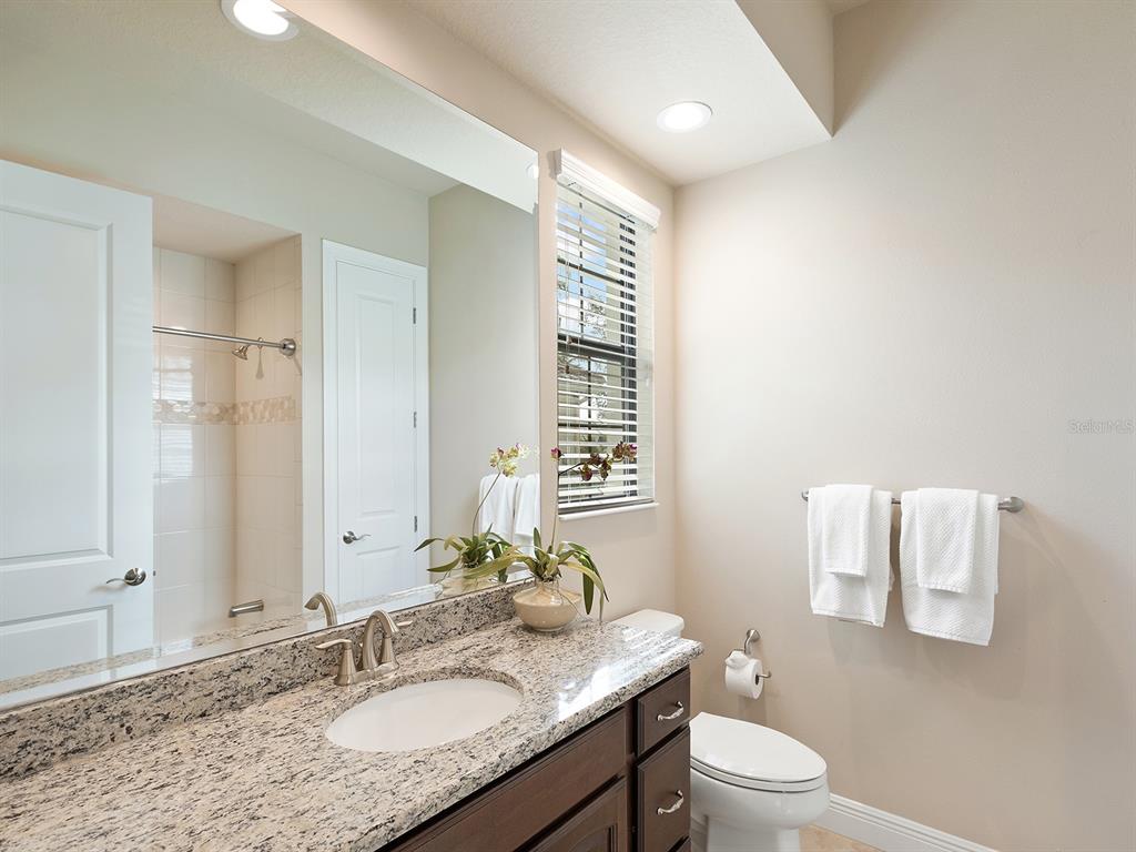 11708 Rive Isle Run Parrish, FL 34219 - Photo 35 of 65 a bathroom with a granite countertop sink a toilet and a mirror