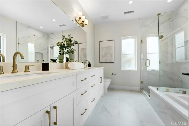 a spacious bathroom with double sink a large mirror a shower and bathtub