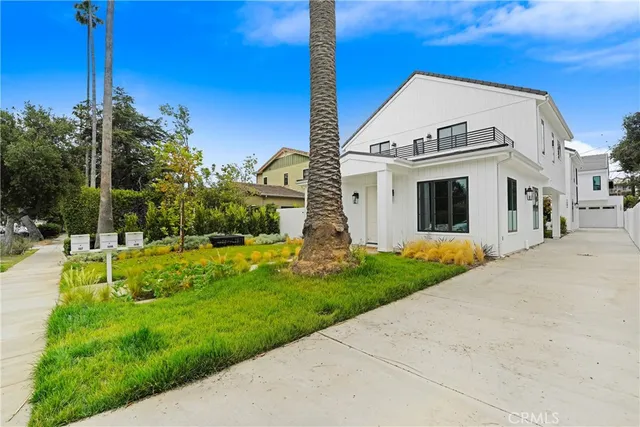 a view of a white house with a big yard and potted plants