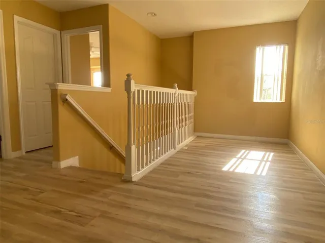 a view of empty room with wooden floor and fan