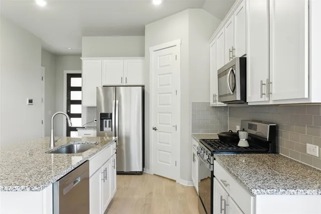 a kitchen with granite countertop white cabinets and stainless steel appliances