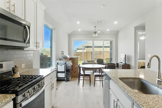 a kitchen with kitchen island granite countertop a sink a stove and cabinets