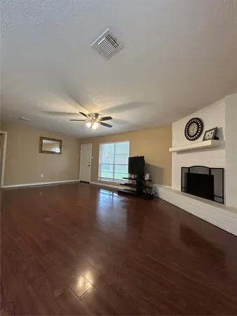 a view of empty room with fireplace and wooden floor