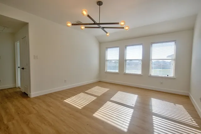 a view of an empty room with window and wooden floor