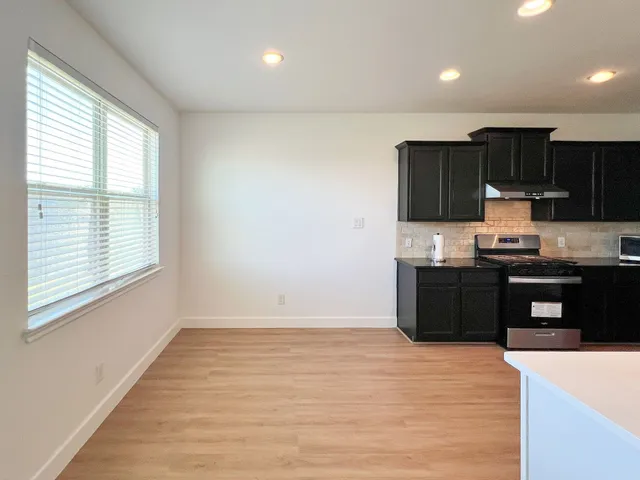 a kitchen with granite countertop a refrigerator and a stove top oven